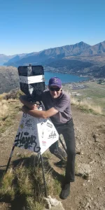 Image of Survey Chainman on hill overlooking mountains and water